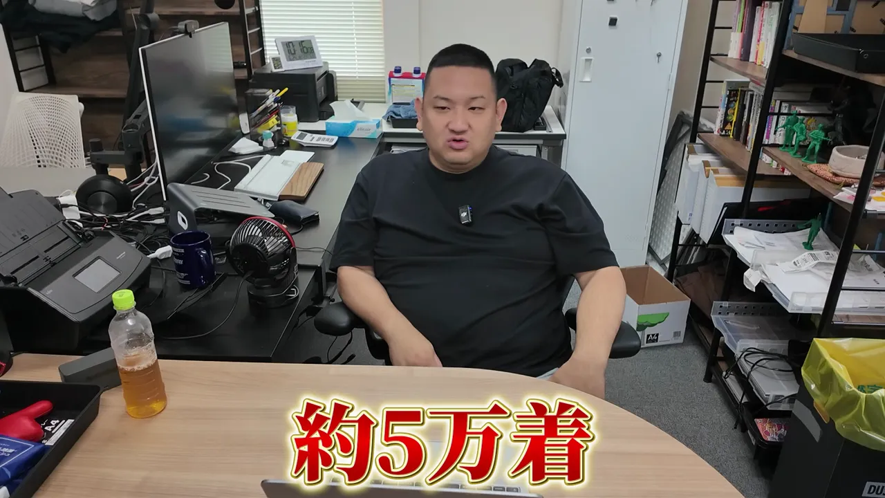 机の前に座る男性と約5万着という大きな文字が表示された画面
