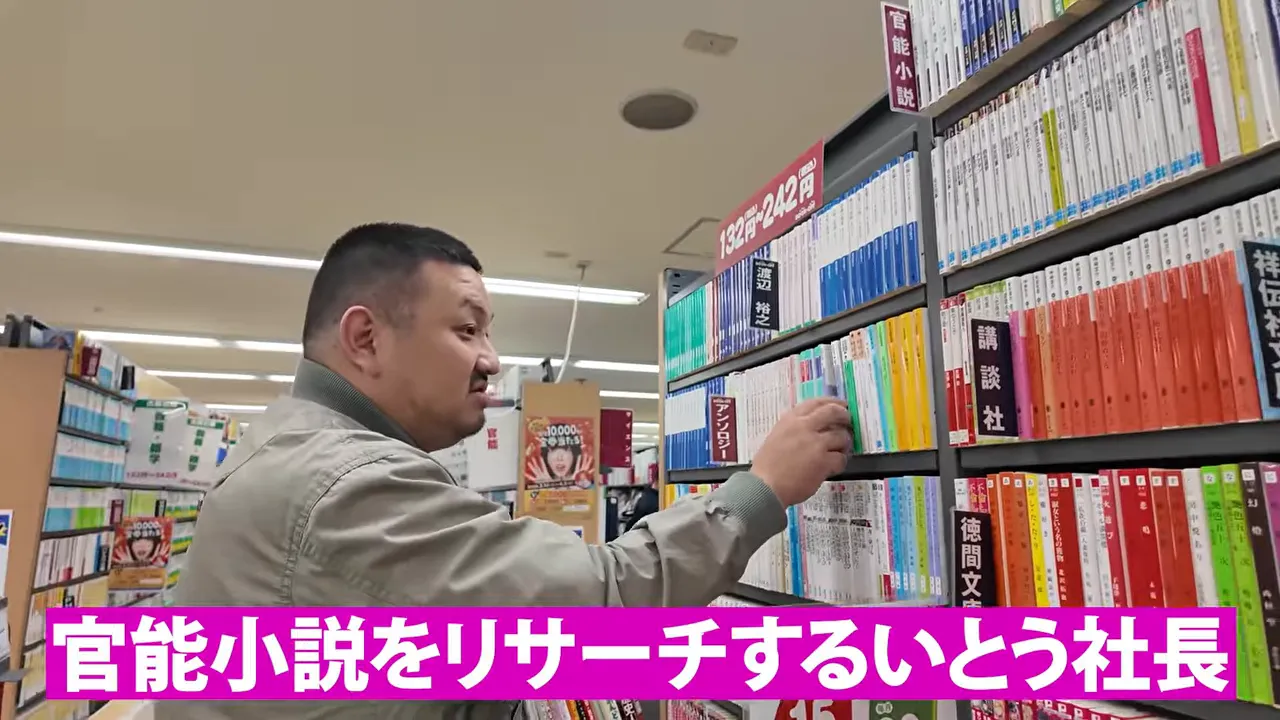 本棚の前で官能小説をリサーチするとテロップ表示されている