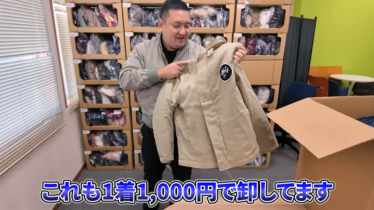 手に持って見せているベージュのジャケット（1着1000円の例）