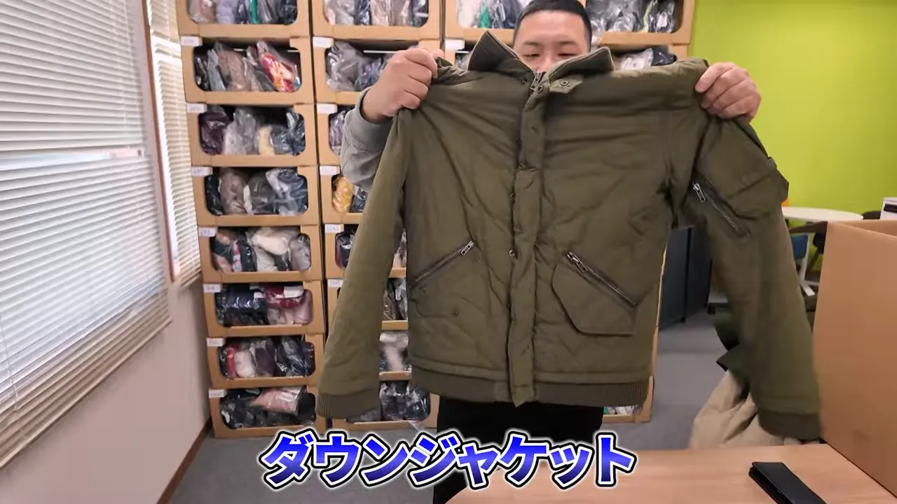 緑のダウンジャケットを手に持って見せる様子