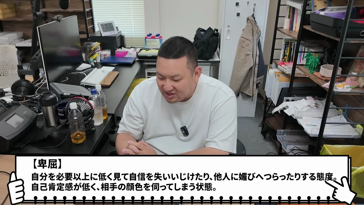 机に座る男性と、卑屈の意味を説明する白いテキスト枠
