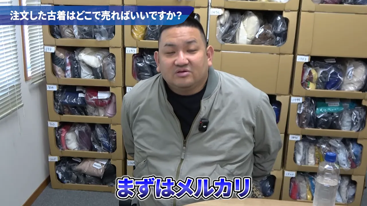 倉庫の段ボール棚を背景に座る男性のカット、画面下部に『まずはメルカリ』と表示されたスクリーンショット