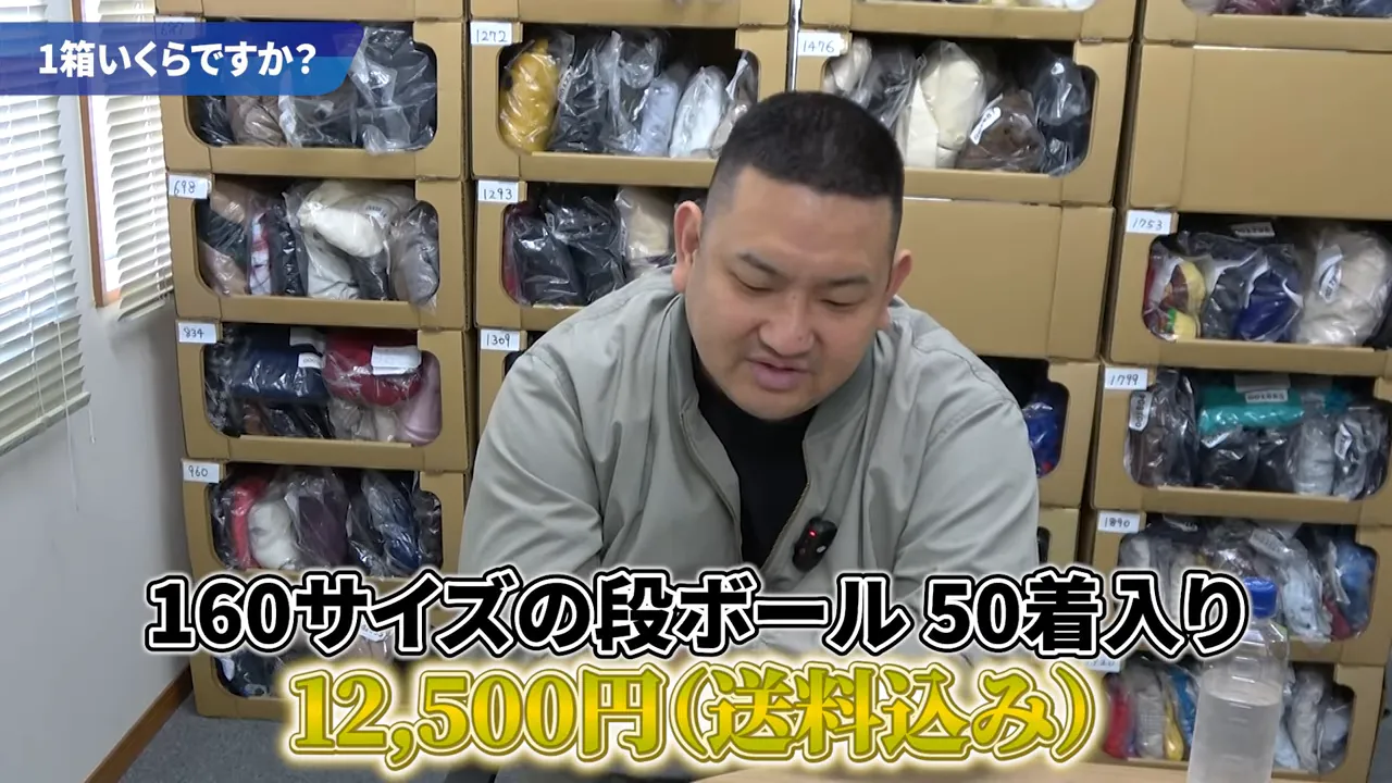 段ボールに詰められた古着の棚を背景に、画面に「160サイズの段ボール50着入り」「12,500円（送料込み）」と大きく表示されたテロップ
