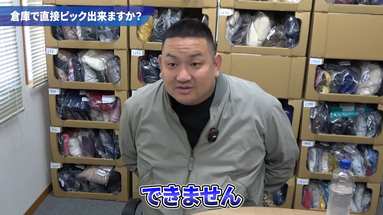 倉庫の棚を背景に説明者が『できません』と回答している画面