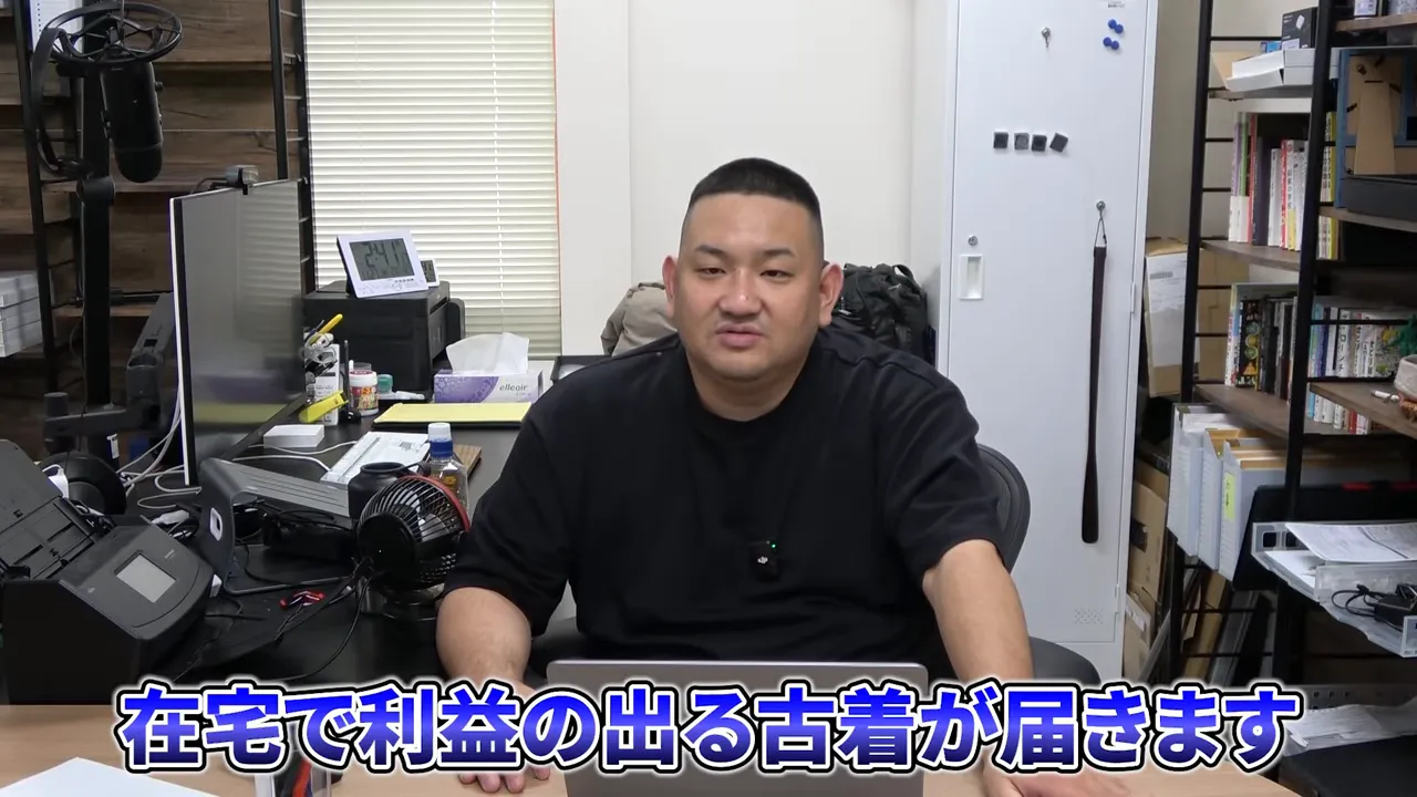 デスクに座って説明する男性と画面下に『在宅で利益の出る古着が届きます』と書かれたテロップ