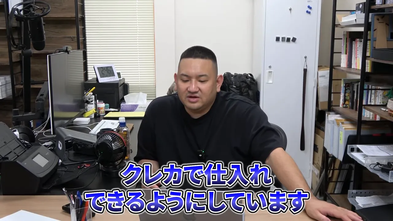 オフィスで説明する人物、下部に『クレカで仕入れできるようにしています』のテロップがある画面