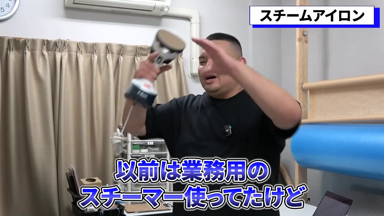 手に持った小型ハンガースチーマーを示しながら使い方を説明する様子