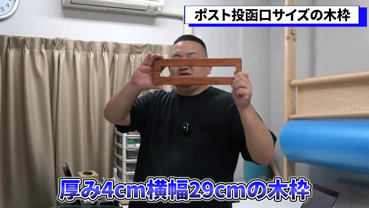 ポスト投函口サイズの木製フレームを持ち、正面からフレームの形状がはっきり見える写真