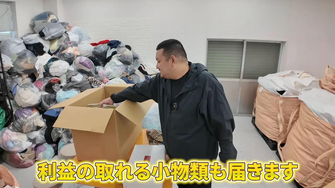 倉庫で段ボールを開封して古着・服飾小物を確認する様子