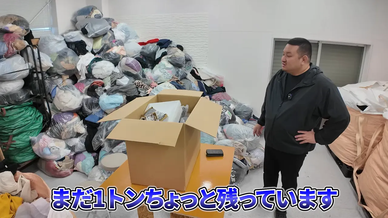 古着を大量に扱う倉庫で説明するスタッフ(服以外も利益商品が出る)