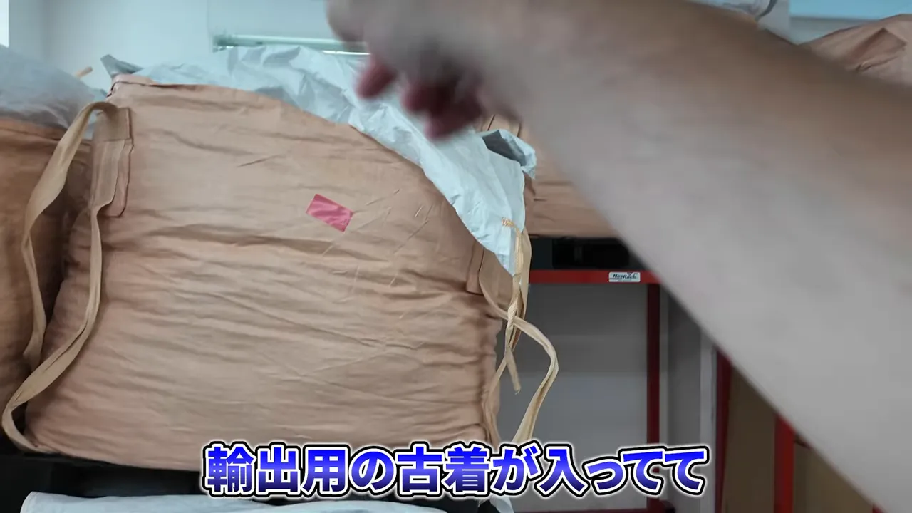 赤いラックの上に輸出用古着の大きな茶色い袋が並んでいる