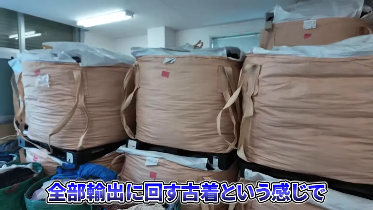 ピンク色のテープが付いた茶色い大袋が倉庫のラックに並んでいる