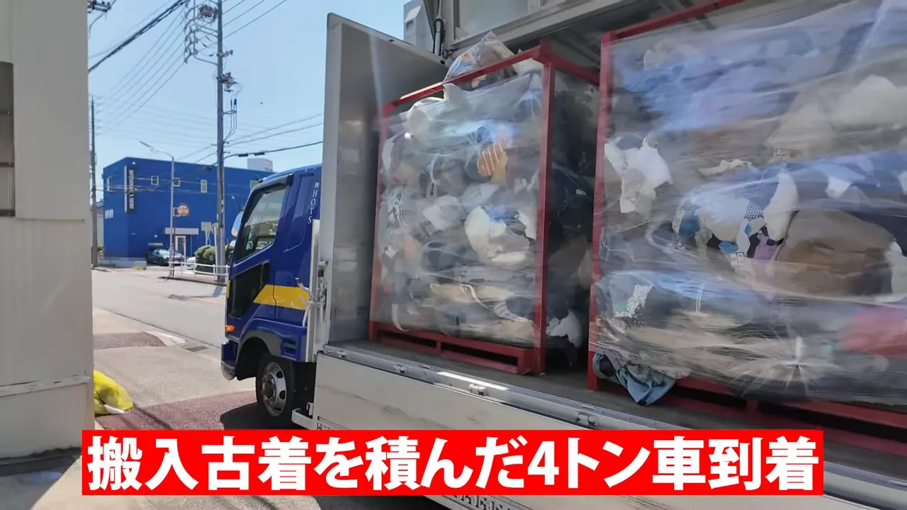 トラックの開いた荷台に袋入りの古着を積んだ赤い大型枠が並んでいる