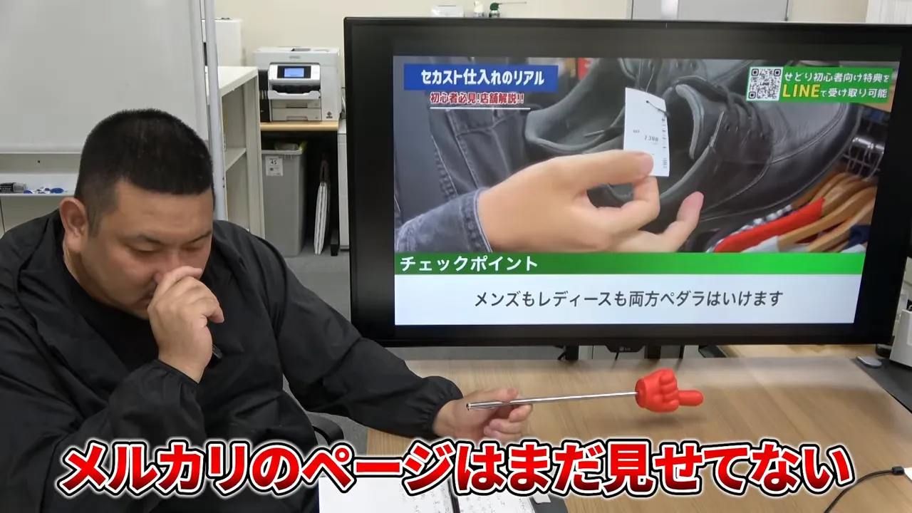 モニターに黒い革靴が映り、メルカリのページはまだ見せていないという字幕が表示されている場面