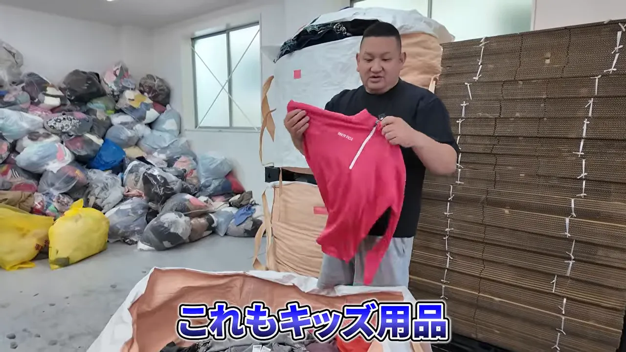 倉庫内で赤い子供服を手に持つ男性