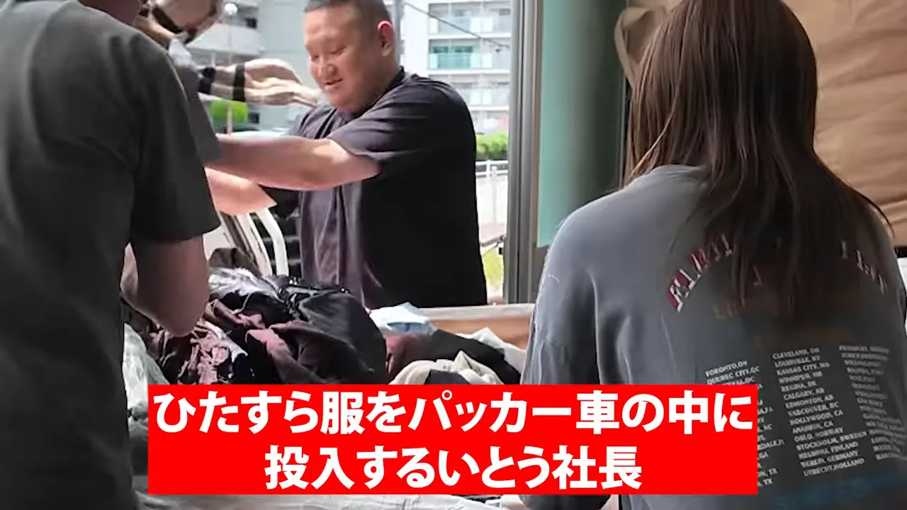 複数人が倉庫の入口で古着を回収車へ投入している様子