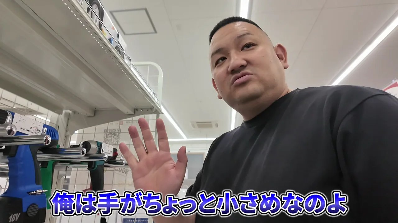 工具売り場で黒い電動工具を手に持って確認している様子