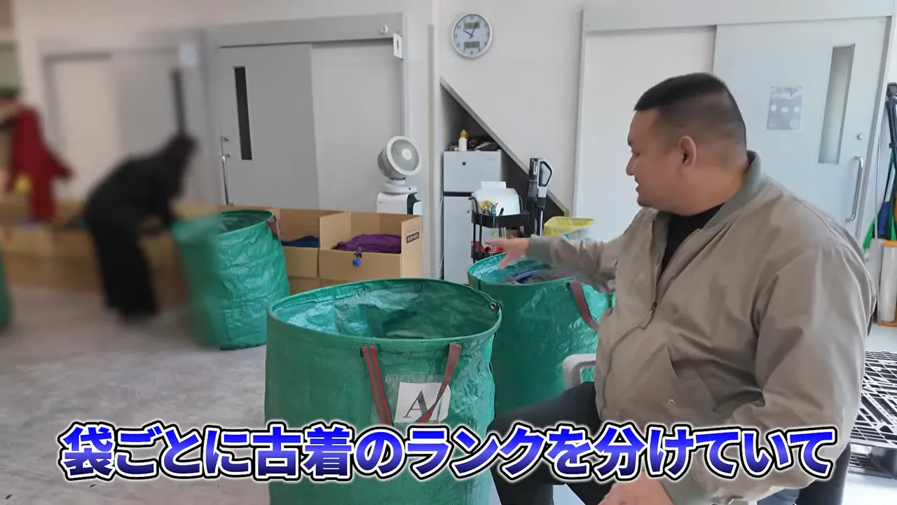 緑の大きな袋と箱を前にしてランク分けを説明している様子