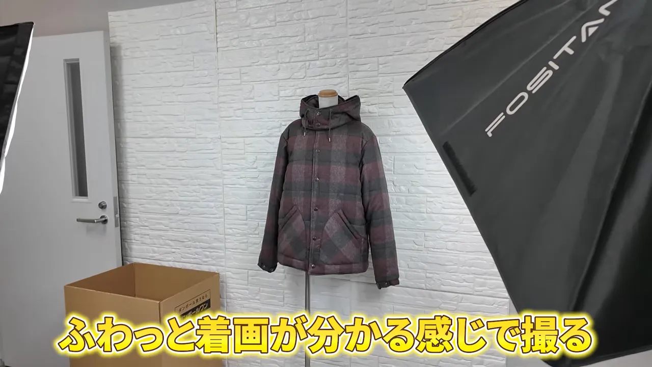 白い壁の前でトルソーに着せたチェック柄ジャケットと撮影用ライト