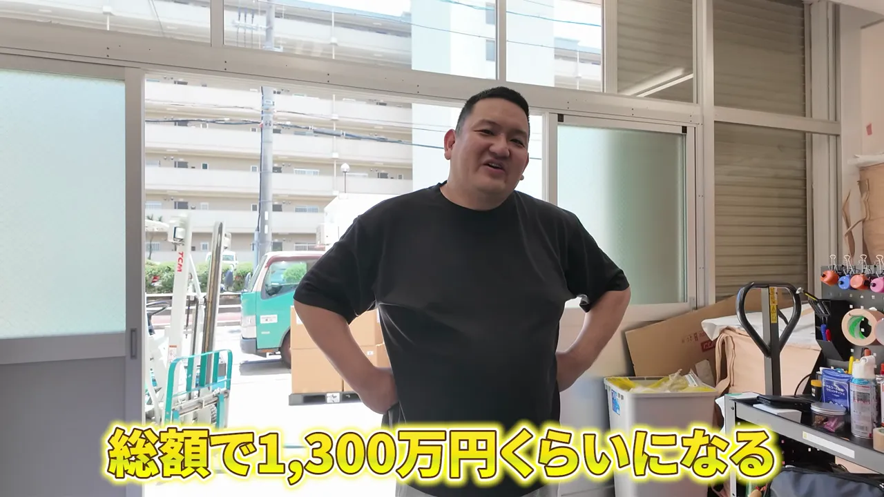 倉庫入口付近でスタッフが立ち、総額1,300万円くらいになるという字幕が表示されている場面