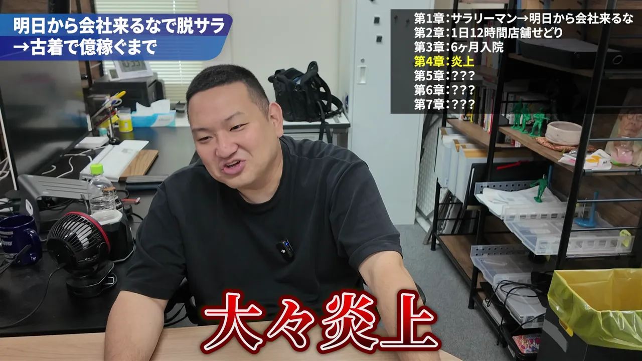 机に座る男性と、大炎上という赤い字幕