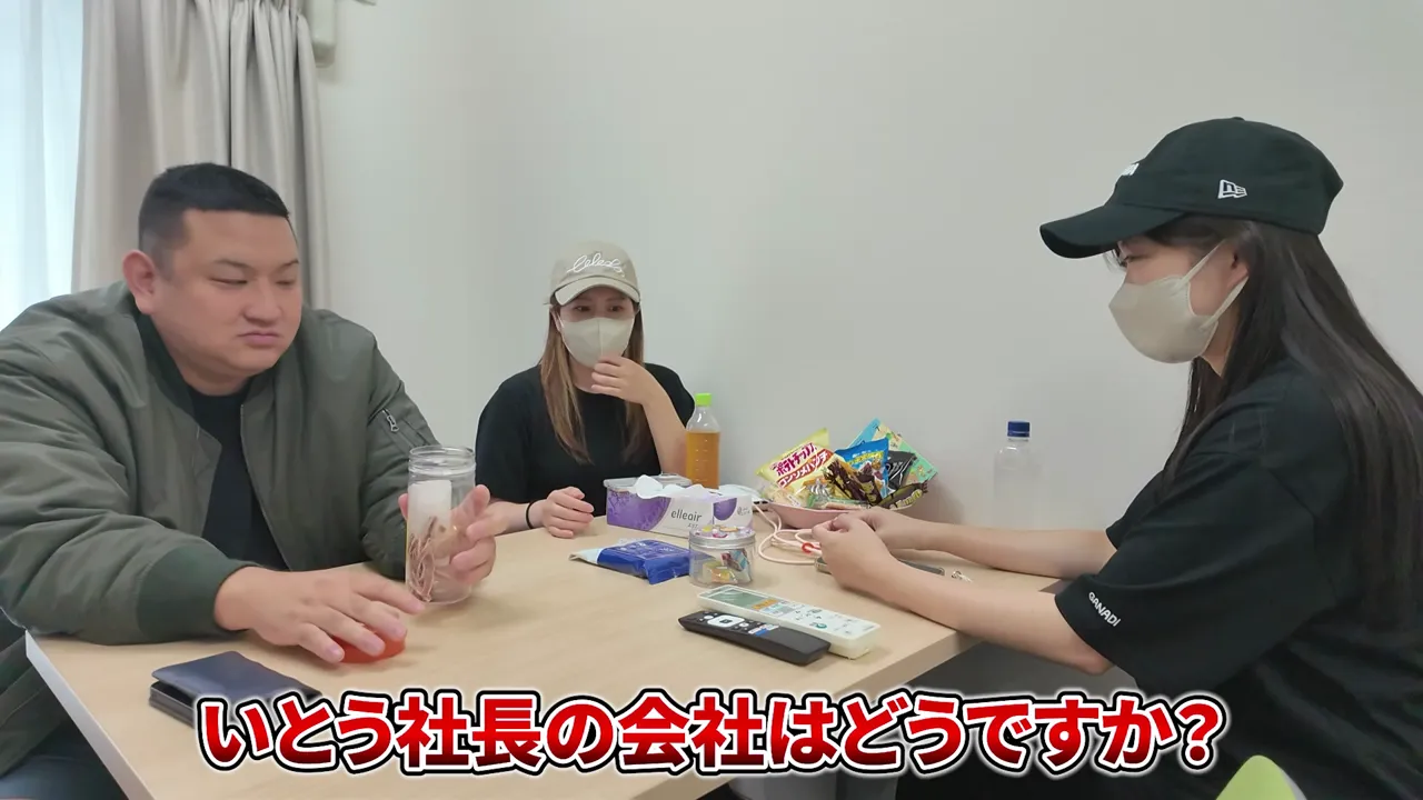 休憩室のテーブルに菓子の入ったかごや飲み物が並び、スタッフがかごに手を添えている様子