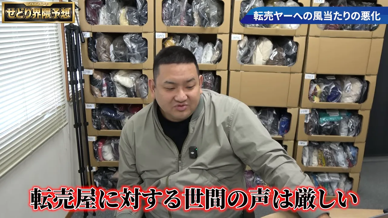 段ボール棚を背景に「転売屋に対する世間の声は厳しい」と赤い字幕で表示されたインタビュー画面