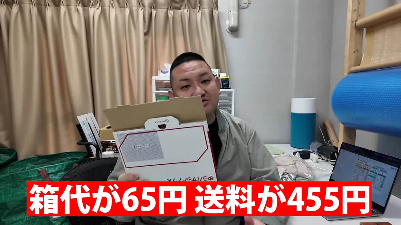 男性が箱を持ち、画面下に大きく箱代65円と送料455円のテロップがある写真