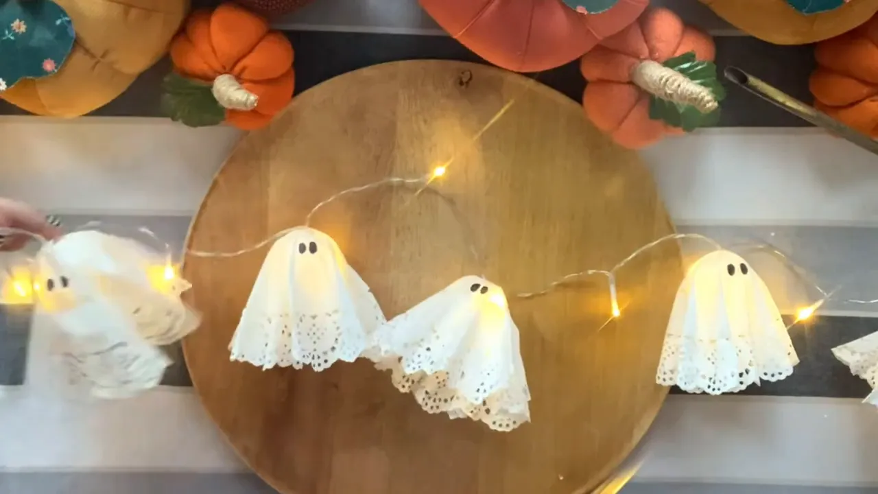 Paper doily ghosts attached to glowing string lights