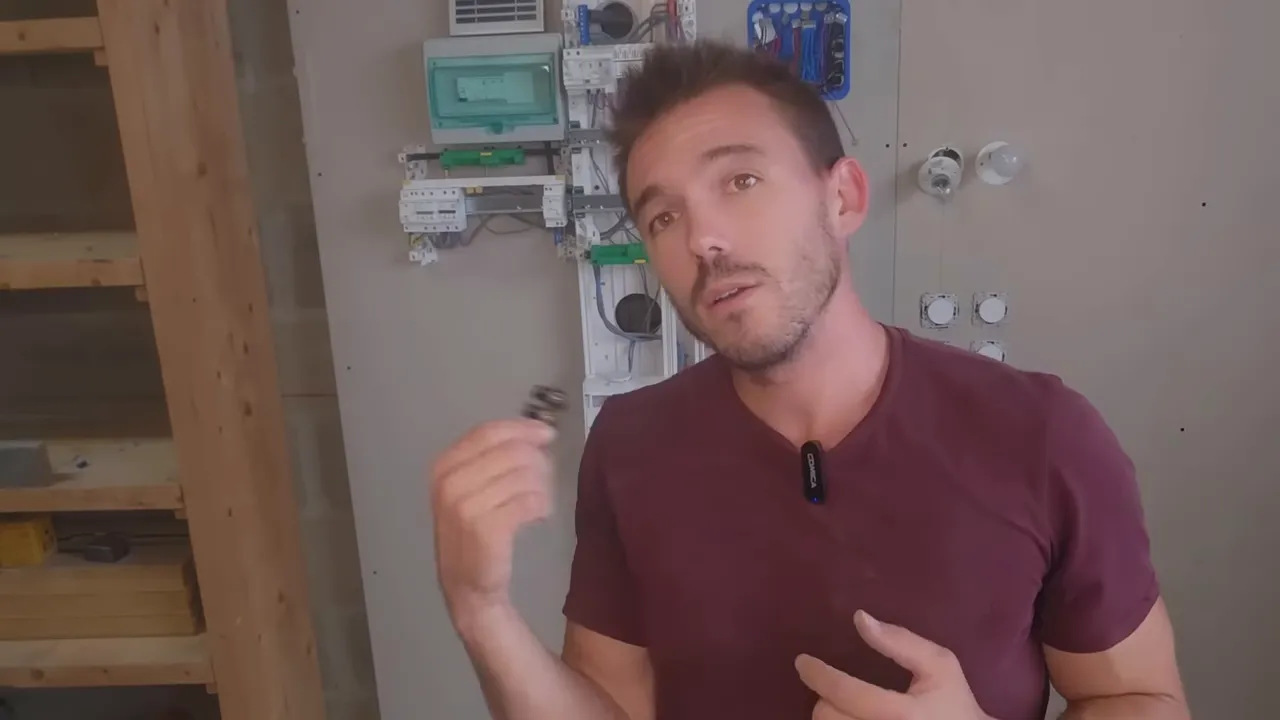 Gros plan du présentateur tenant un petit connecteur électrique devant un tableau d'entraînement