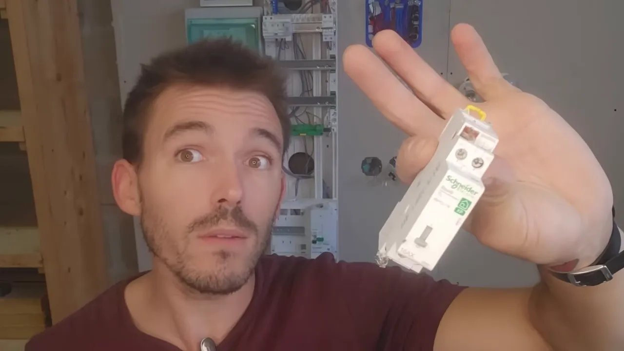 Gros plan net d'un module Schneider (télérupteur/contacteur) tenu en main devant un tableau électrique d'entraînement