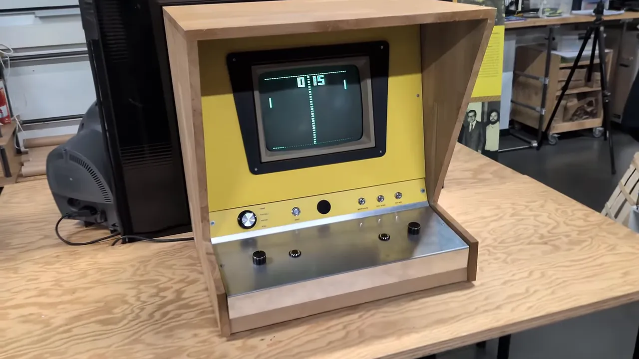 Petit bartop en bois avec façade jaune, écran Pong et commandes rotatives