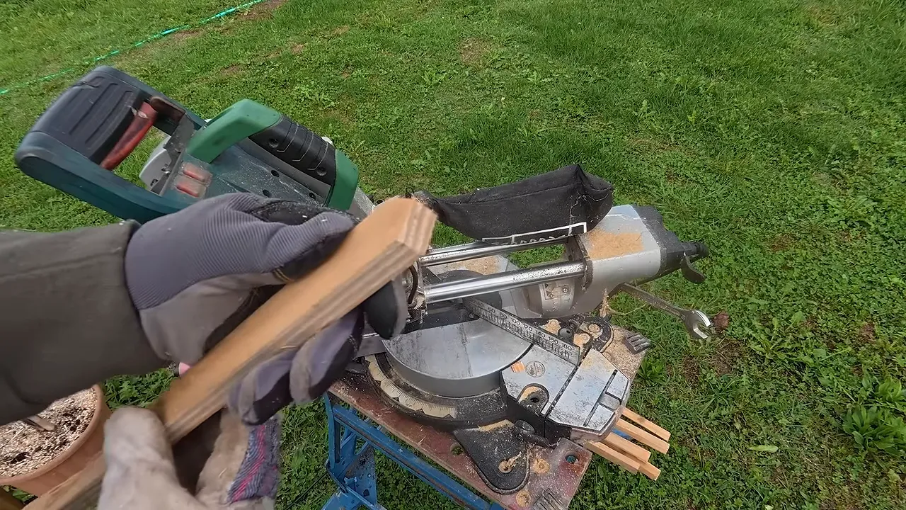Latte de bois tenue devant une scie à onglet, avec une extrémité taillée en pointe