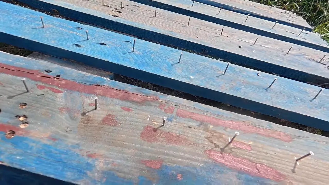 Planches d’une palette bleue portant plusieurs rangées de clous espacés