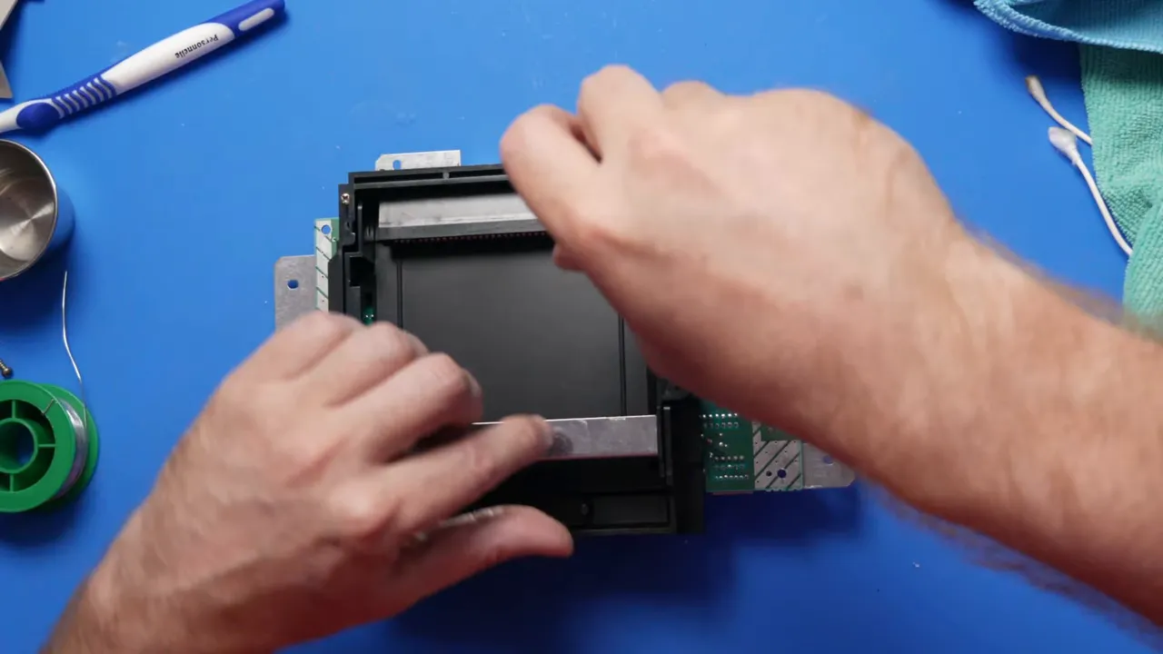 Mains installant le mécanisme du plateau de cartouche dans une NES ouverte
