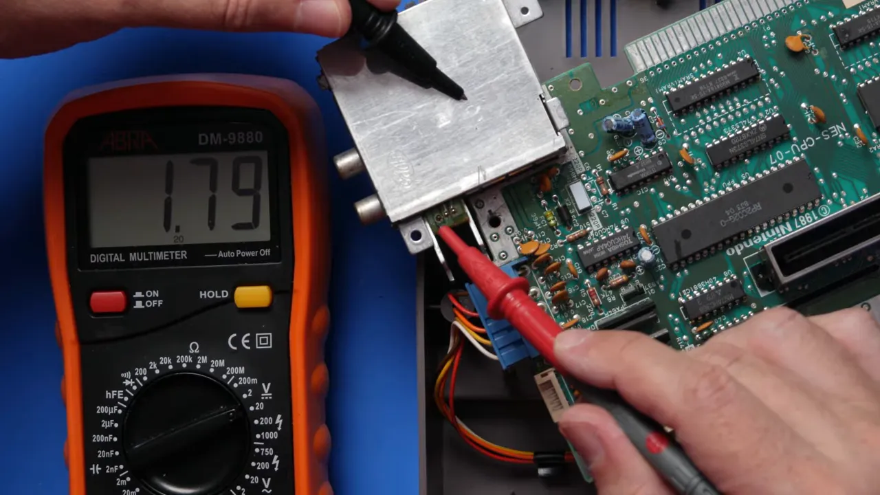 Multimètre branché sur la carte mère de NES affichant une mesure de 5,02 volts