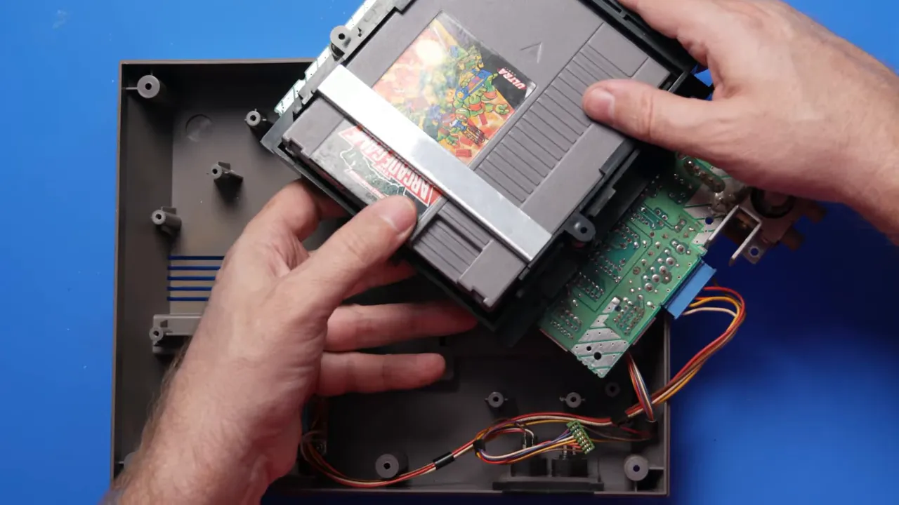 NES ouverte avec plateau de cartouche, connecteur et jeu installés pour le test