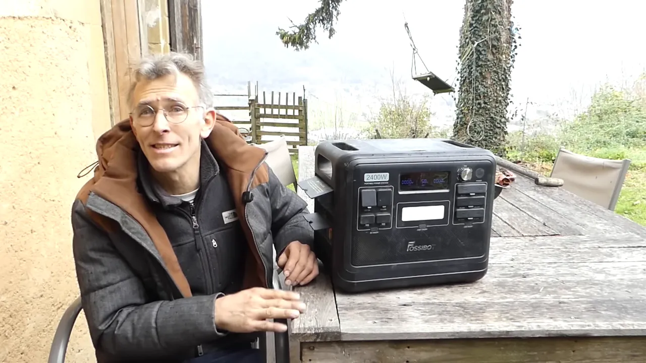 Station solaire FOSSiBOT F2400 posée sur une table extérieure à côté de l'auteur, écran et prises visibles