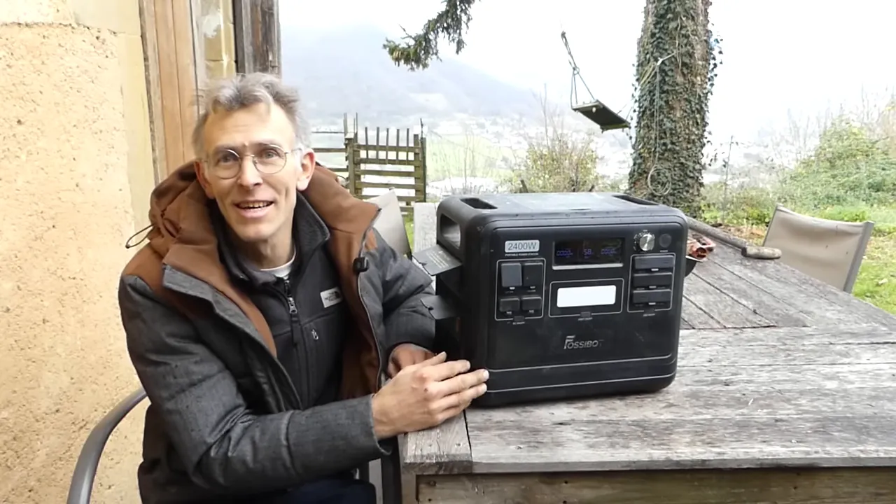 Gros plan montrant la station portable FOSSiBOT F2400 posée sur une table, avec la main de l'animateur sur le boîtier