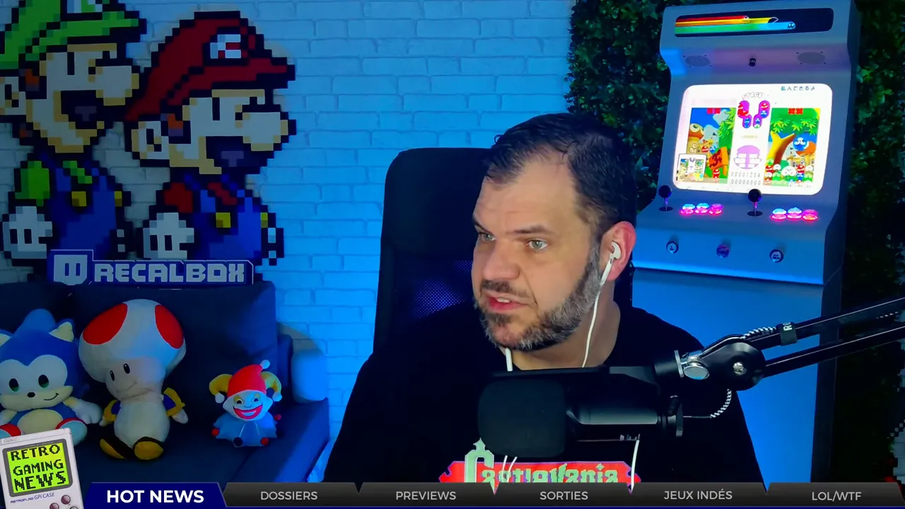 animateur en streaming avec une mini-borne d'arcade rétro affichant un jeu coloré en arrière-plan