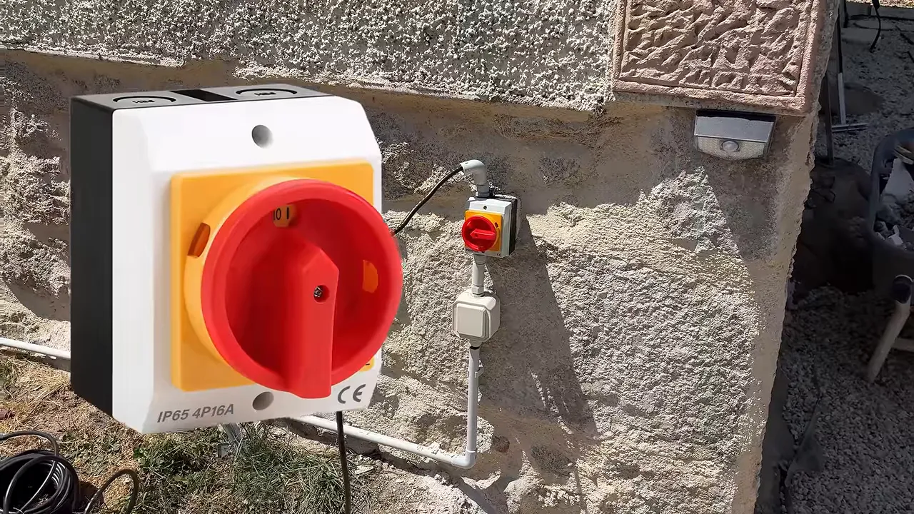 Prise électrique extérieure rouge installée sur un mur en pierre