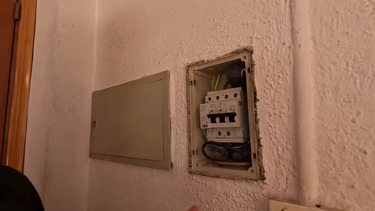 Petit coffret électrique ouvert contenant un disjoncteur et des câbles