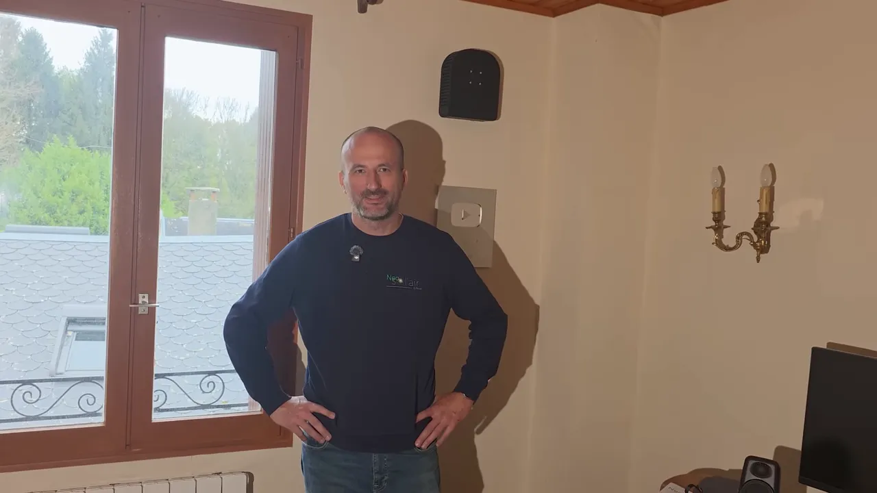 Intervenant Neo Sol’air dans la pièce d’essai devant une fenêtre et un boîtier mural