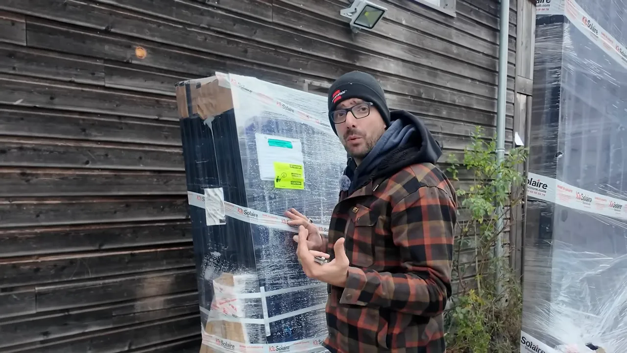 Moi présentant des palettes de panneaux solaires emballés avant installation