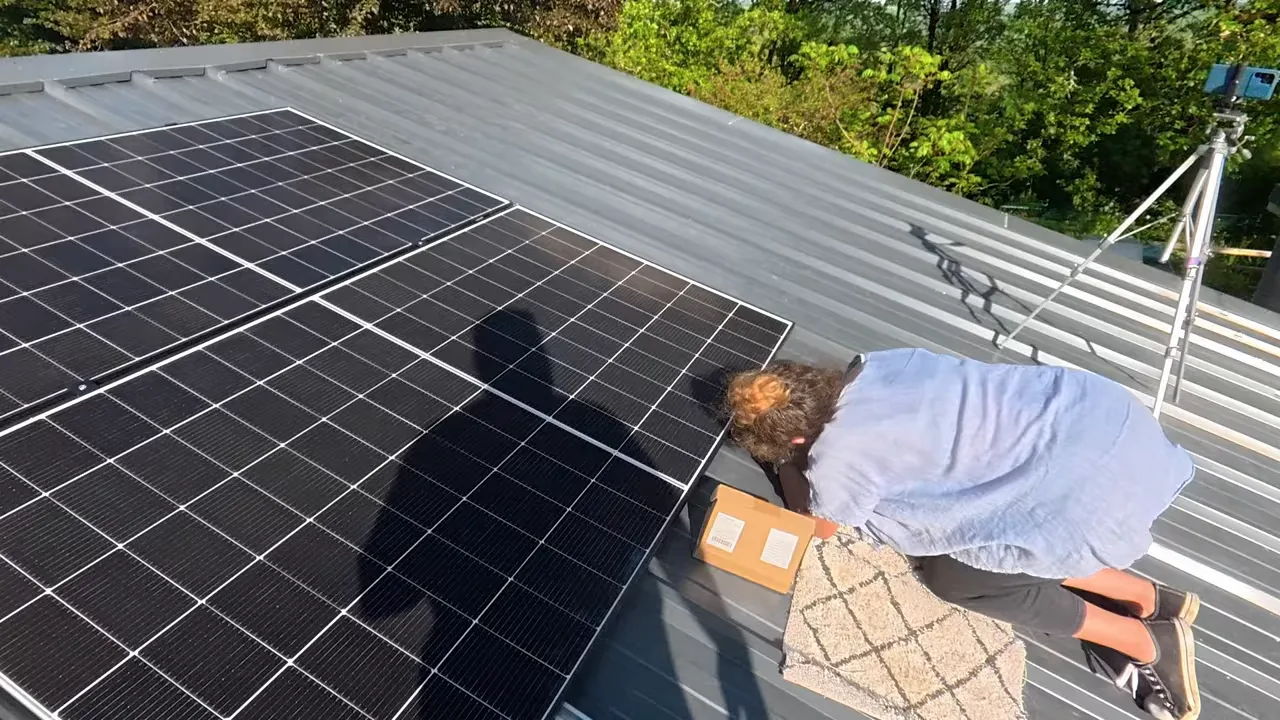 Pose de panneaux solaires sur toiture en bac acier avec un installateur au travail sur la rangée de modules