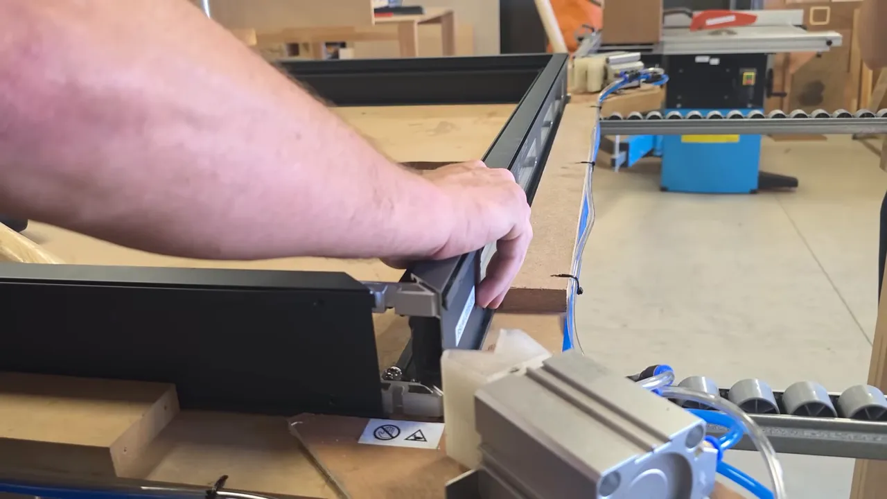 Main d'opérateur ajustant le cadre d'un panneau aérothermique en atelier