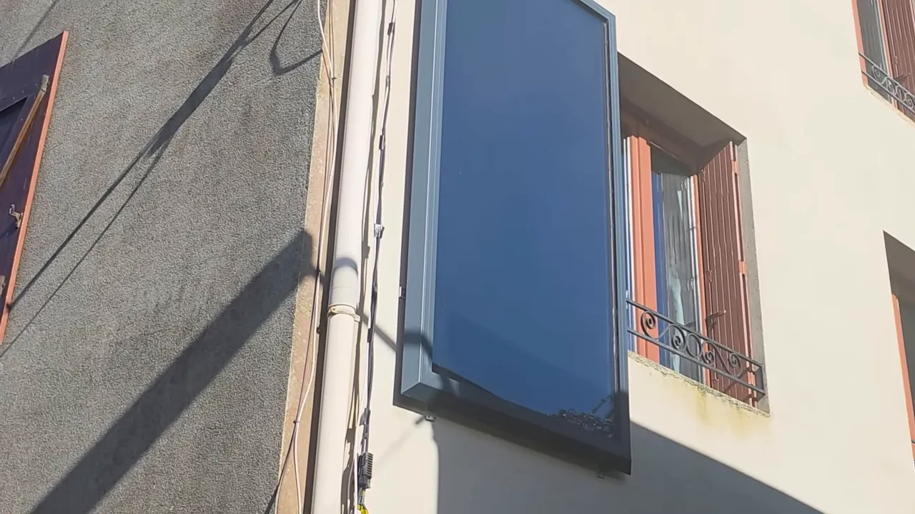Panneau aérothermique noir monté sur une façade extérieure près d'une fenêtre