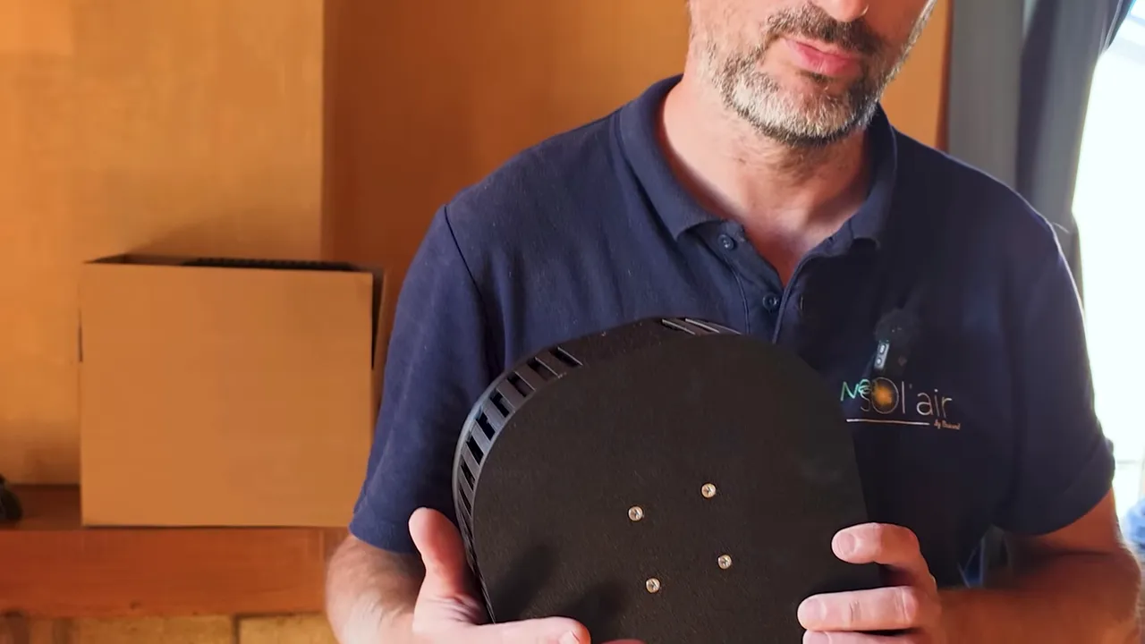 Présentateur tenant le boîtier de ventilation montrant les aérations et la fixation