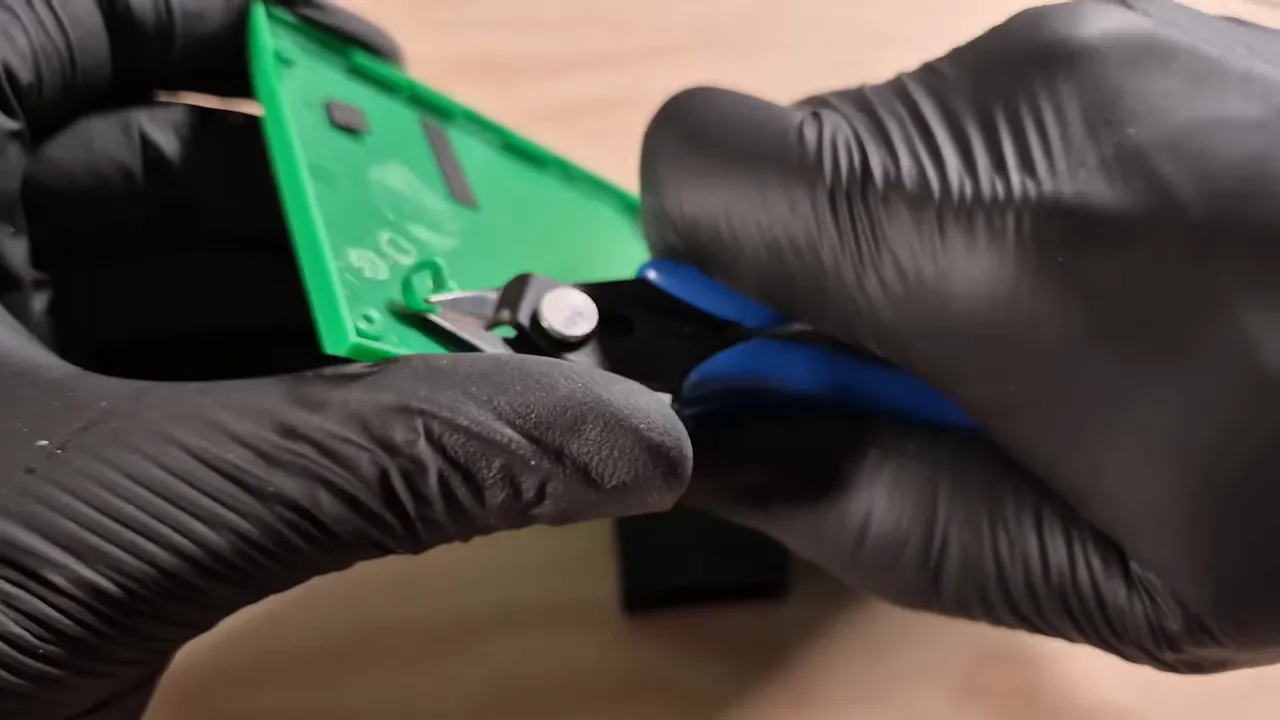 Gants en train d’ajuster une pièce de coque verte pour créer l’ouverture microSD