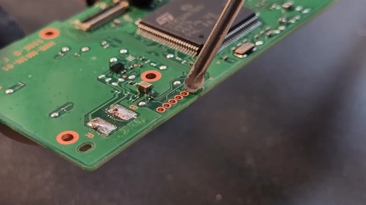 Fer à souder réalisant une connexion sur la carte mère de la Game & Watch Zelda